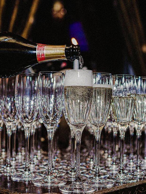Champagne being poured into a row of glasses for guests